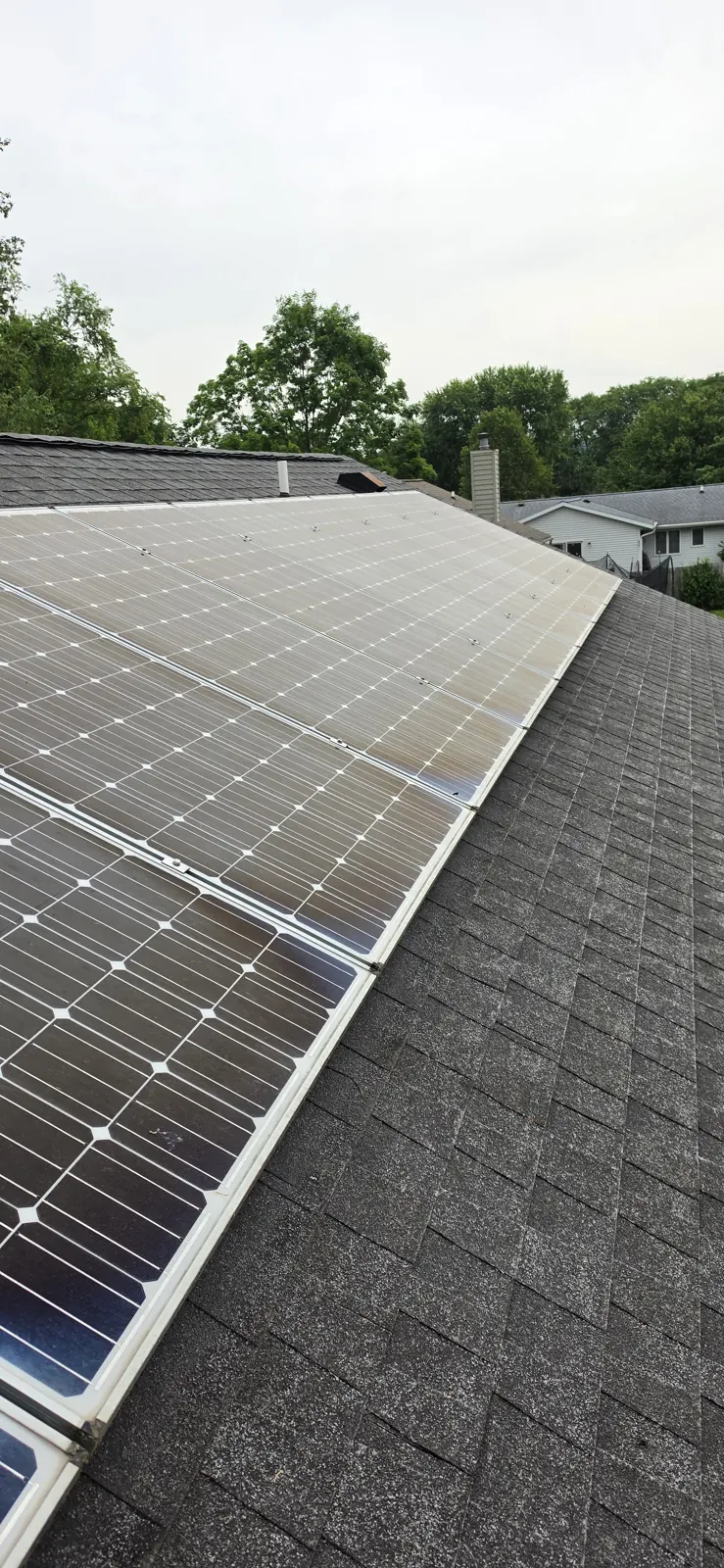 Solar panels after 8 years without a professional cleaning, hazy, milky film across every cell from stacked seasons of pollen, hard-water residue, and airborne particulate