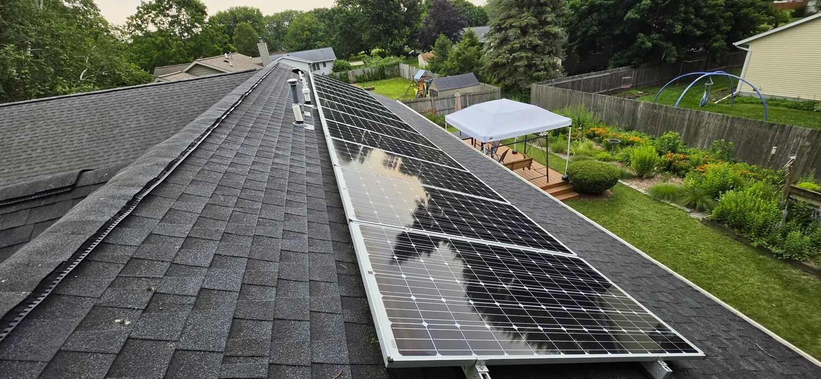 Same solar array immediately after a Solar Alchemist clean, cumulus clouds visibly reflected on the glass