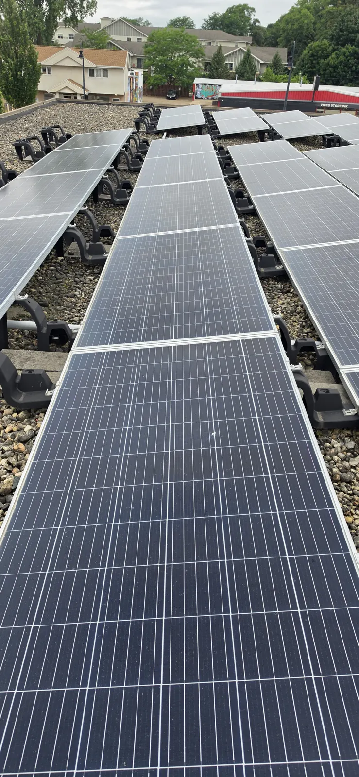 Wide view of a large commercial rooftop solar array after cleaning, rows of dark panels