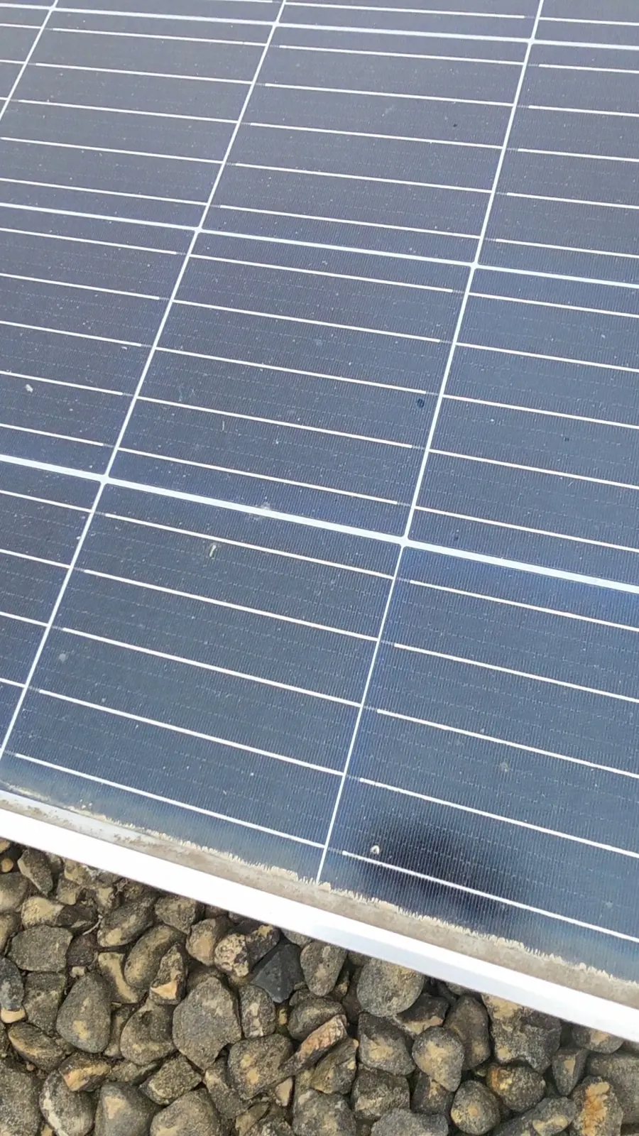 Close-up of a baked film of dust built up along the bottom edge of a solar panel