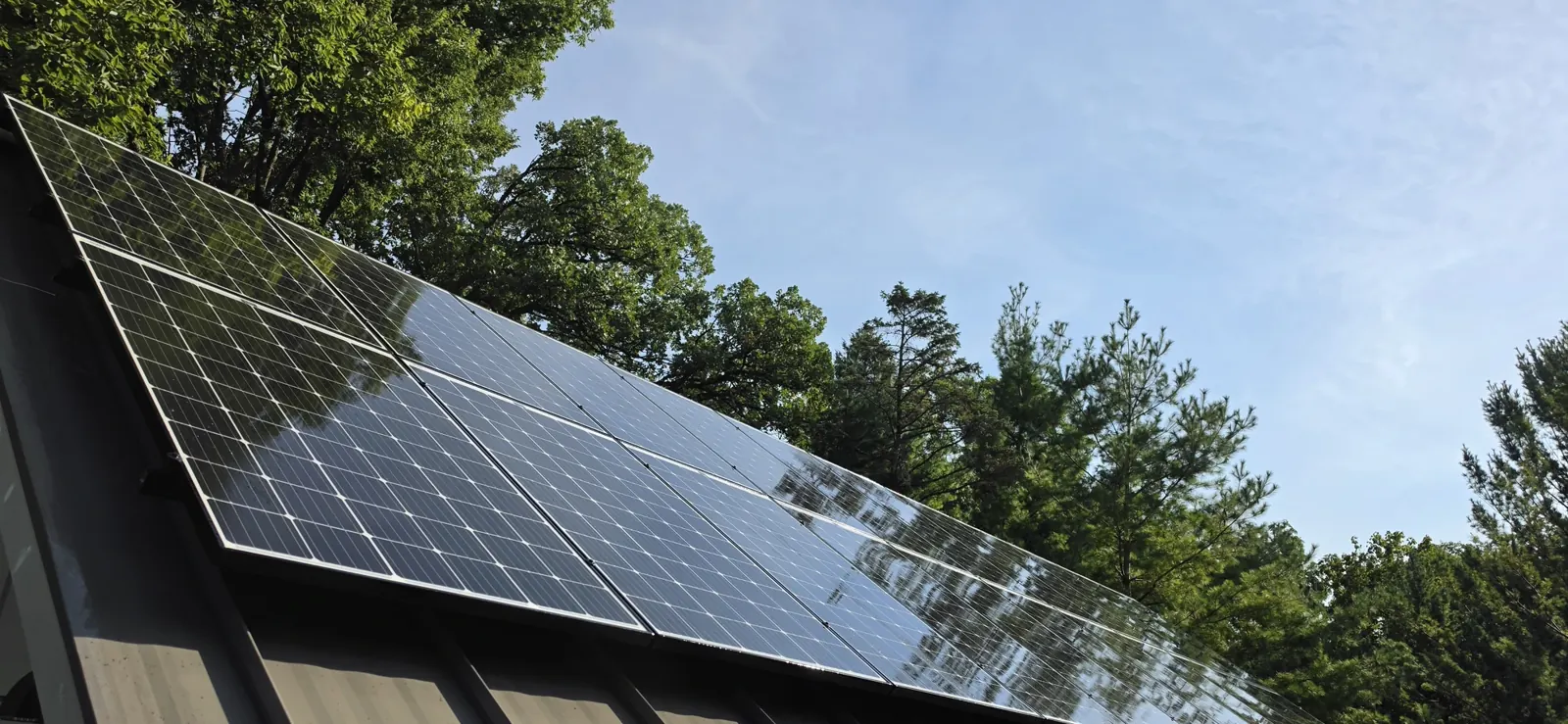 Same Southern Wisconsin residential solar array on a standing-seam metal roof photographed at 9:22 AM after Solar Alchemist cleaning, the glass is dark, uniform, and mirror-clean