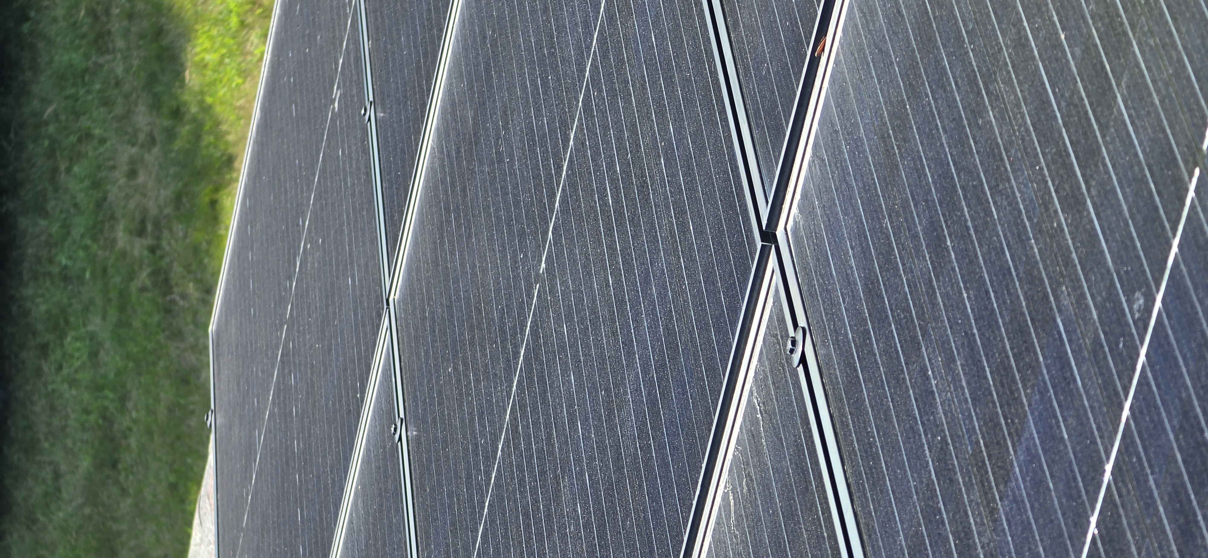Front-pitch rooftop solar array in Dane County with visible white hard-water striations and settled ambient dust running across the panel glass